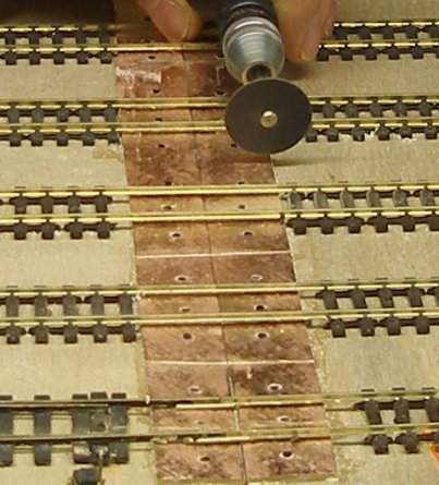 The copperclad is cut through between each rail, both between the two rails of each track, and the strip in between tracks to prevent short circuits.