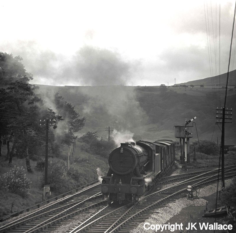 Eric F Bentley caught WD Austerity 2-8-0 90345 at Stansfield Hall (Todmorden) on a westbound mixed freight stopping passing the water tank, and about  to cross the junction before picking-up a banking loco on Saturday 30 July 1966