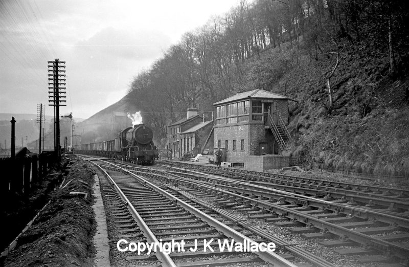 A WD Austerity 2-8-0 drifts pass Eastwood signal box with an eastbound empty mineral train in the early 60s