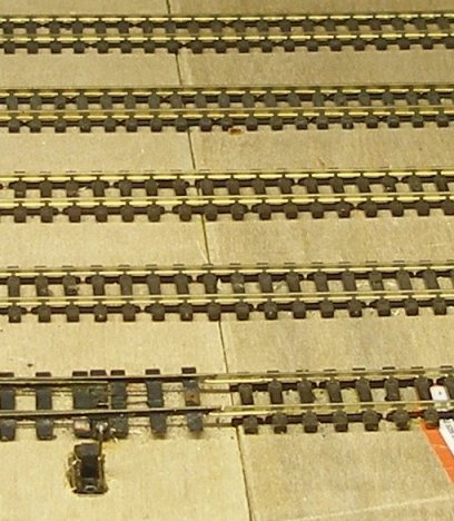 The track has been laid straight across the baseboard joint and pinned down with track nails. Note the copper-clad point in the foreground.