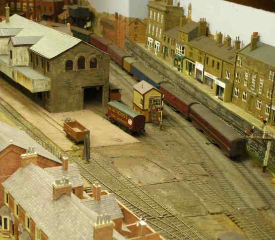 Parcels Train passes a model of Haworth Goods Shed; shops in Burnley Road Todmorden to the right.