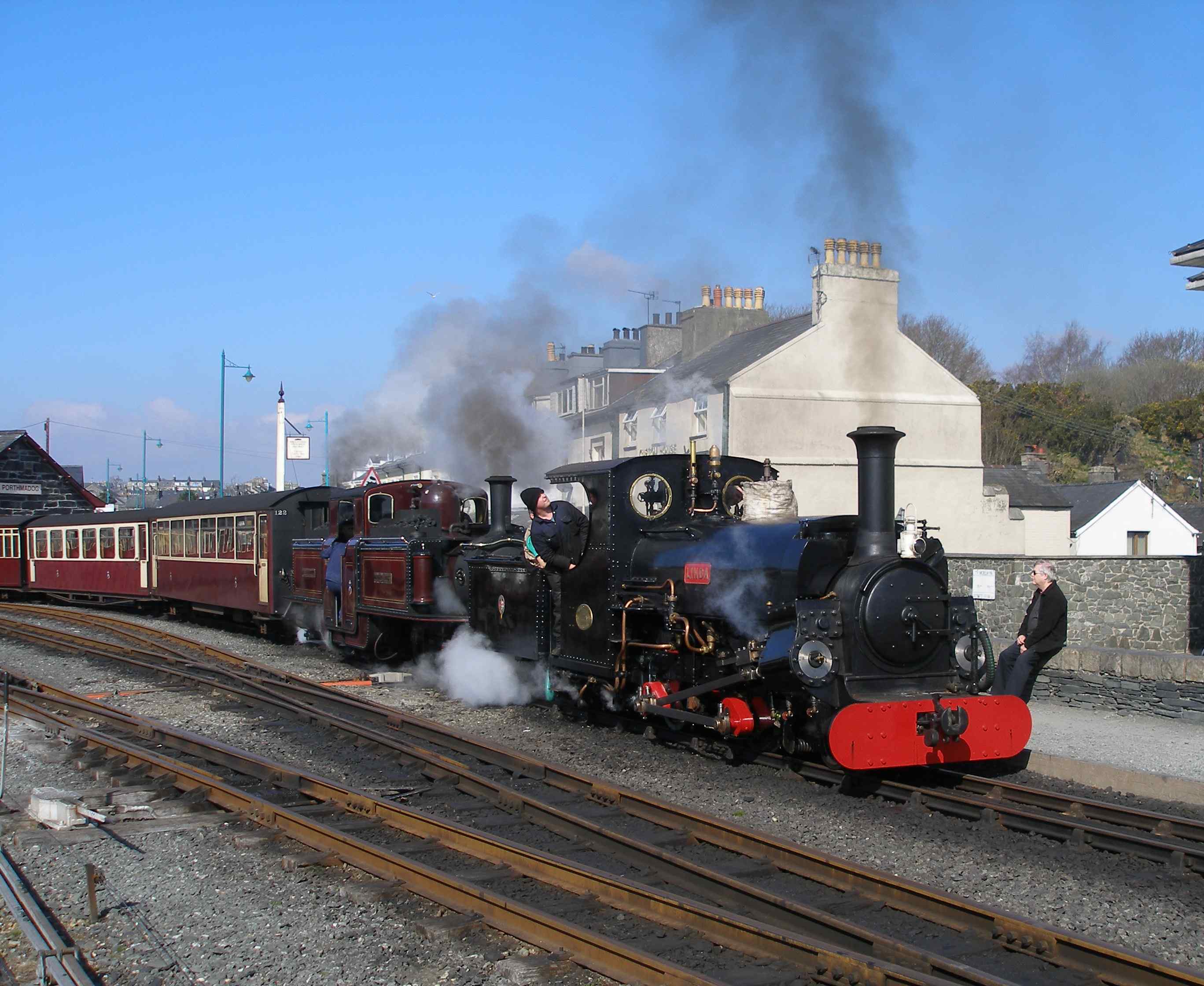'Linda' and 'Merddin Emrys' set off with the empty coaching stock (ecs) for Blaenau Ffestiniog. Both locos were converted to oil firing in the 1970s. This was undertaken as the railway's medium-sized locos had smaller grate areas that reflected their industrial origins ('Linda' and 'Blanche') and therefore were more prone to fire-throwing when worked hard - which was virtually all the time! 'Merddin Emrys' had a better ratio of grate to traffic effort and arguably was less prone to fire throwing and might have been better kept as a coal burner. It's conversion to coal required major work on its tanks, which at the time were virtually brand new. A second set of traditionally-styled tanks were made at the same time for 'Earl of Merioneth' but these have not yet been fitted, and these to will have to be modified for coal.