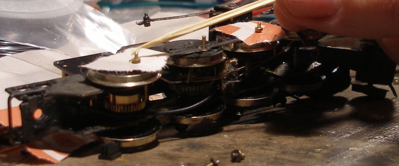 Fitting Romford crank pins -4: Small pieces of newspaper are pushed over the crank pins so that they lie on top of the coupling rod, and then the crank pin bushes are pushed onto the crank pins. A small blob of flux paste is then applied to the top of the crank pin and top surface of the bush. Note that the middle pin is left till later.